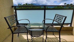 A balcony with a glass table and two chairs, a tiled floor, and a view of mountains and palm trees. - Lins Ju Homestay (Yuchi)
