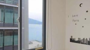 Habitación con un amplio ventanal que da a un paisaje urbano, una pared con una ilustración de un cielo estrellado y una vista parcial de un edificio exterior.
