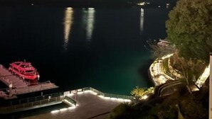 Vista nocturna de una zona costera con un muelle y un edificio iluminado.