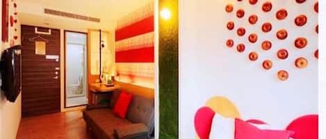A hotel room with a bed, a sofa, a wall with circular decorations, and a door leading to another room.