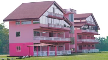 A multi-story pink building with balconies and a covered area.