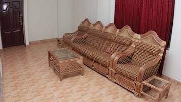 A room with a wicker sofa, a glass-top coffee table, and a small side table.