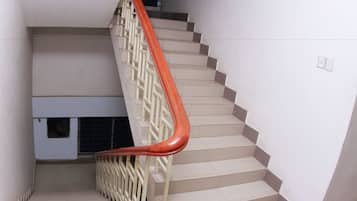 A staircase with beige steps and a red handrail.
