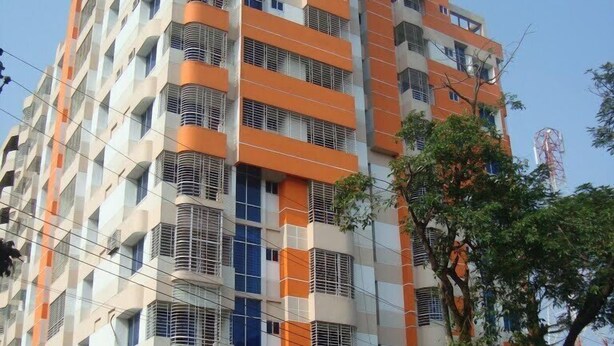 A multi-story building with a modern architectural design, featuring balconies and large windows. - Hillside Holiday Home (Sylhet)