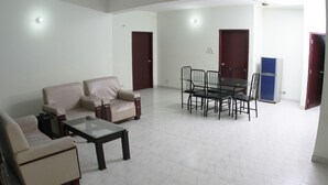 A spacious living area with a sofa set, a coffee table, and a dining table with chairs. - Hillside Holiday Home (Sylhet)