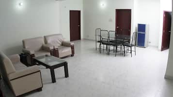 A spacious living area with a sofa set, a coffee table, and a dining table with chairs.