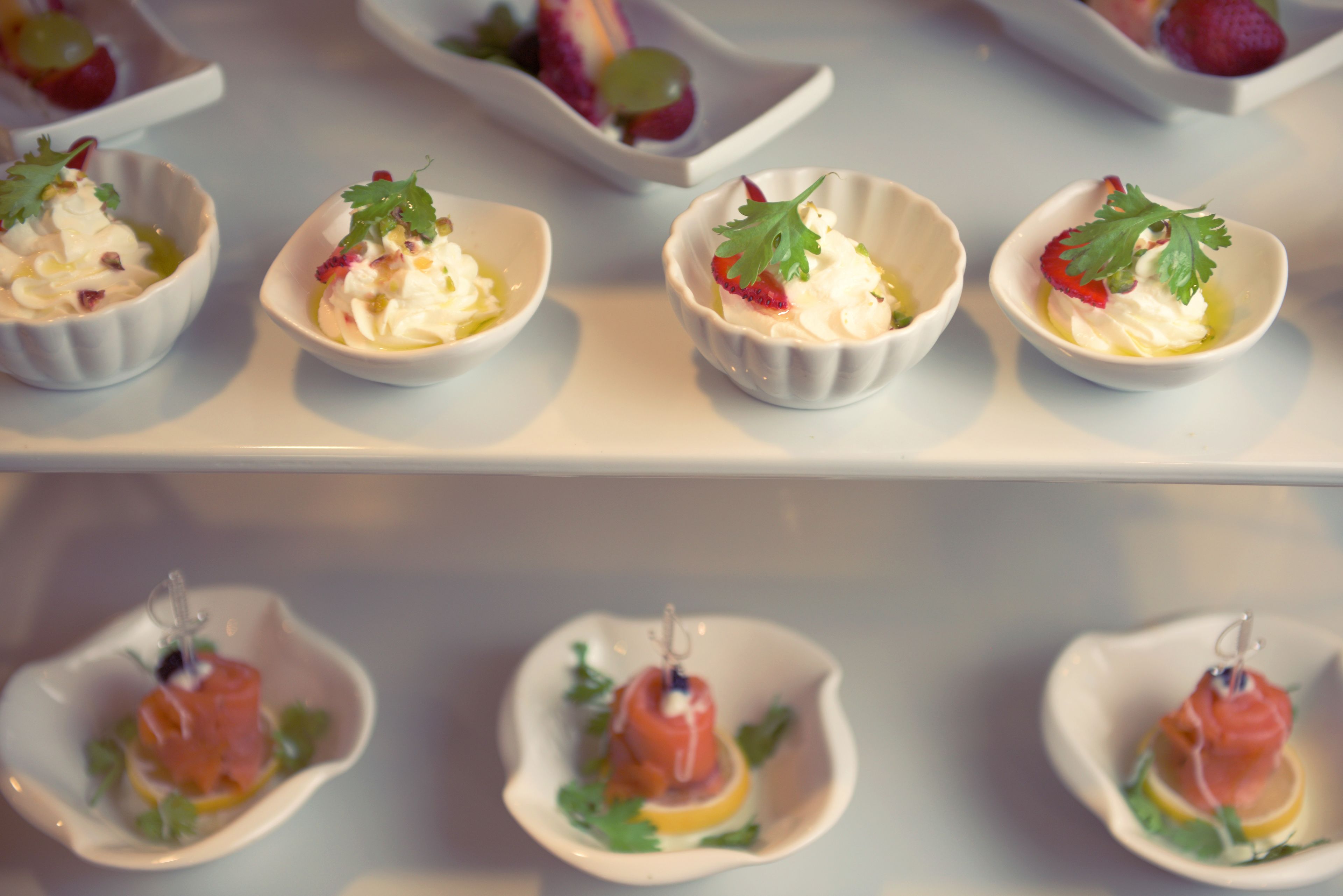 A series of small bowls containing various food items, likely appetizers, arranged on a table.