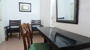 A room with a long black table, two wooden chairs with green cushions, a framed picture on the wall, and a mirror. - Pakdee House (Udon Thani)