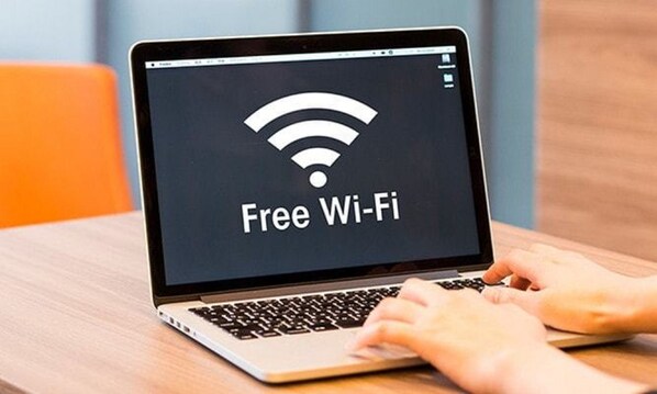 A laptop with a screen displaying "Free Wi-Fi" on a wooden table. - Smile Hotel Nara (Nara)