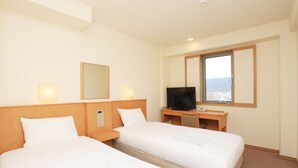 Habitación de hotel con dos camas, televisor, escritorio con computadora y ventana con vistas.
