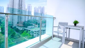 Un balcon doté d’une balustrade en verre, une petite table avec un pot de fleurs et une chaise.