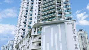Un immeuble moderne de grande hauteur, doté de nombreux balcons et d’une entrée abritée.