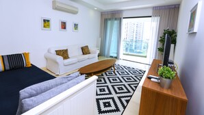 Une chambre d’hôtel moderne équipée d’un lit, d’un canapé, d’une table basse, d’une télévision et d’un balcon avec des rideaux.
