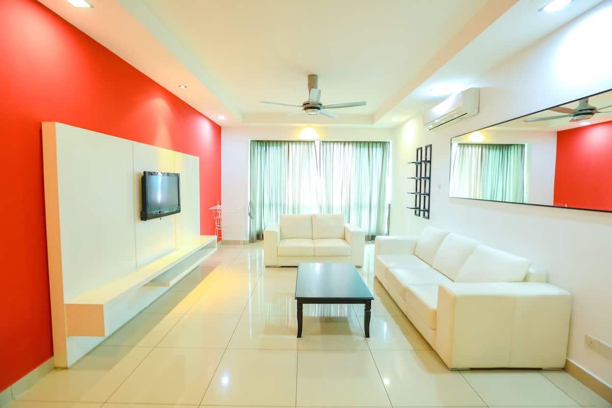 A modern living room with a flat-screen TV, two white sofas, a coffee table, and a ceiling fan.