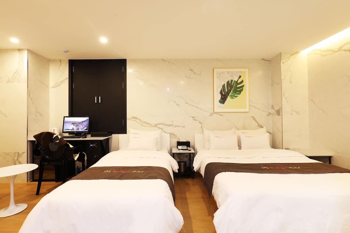 Una habitación de hotel con dos camas, un escritorio con computadora, una silla y una mesita.