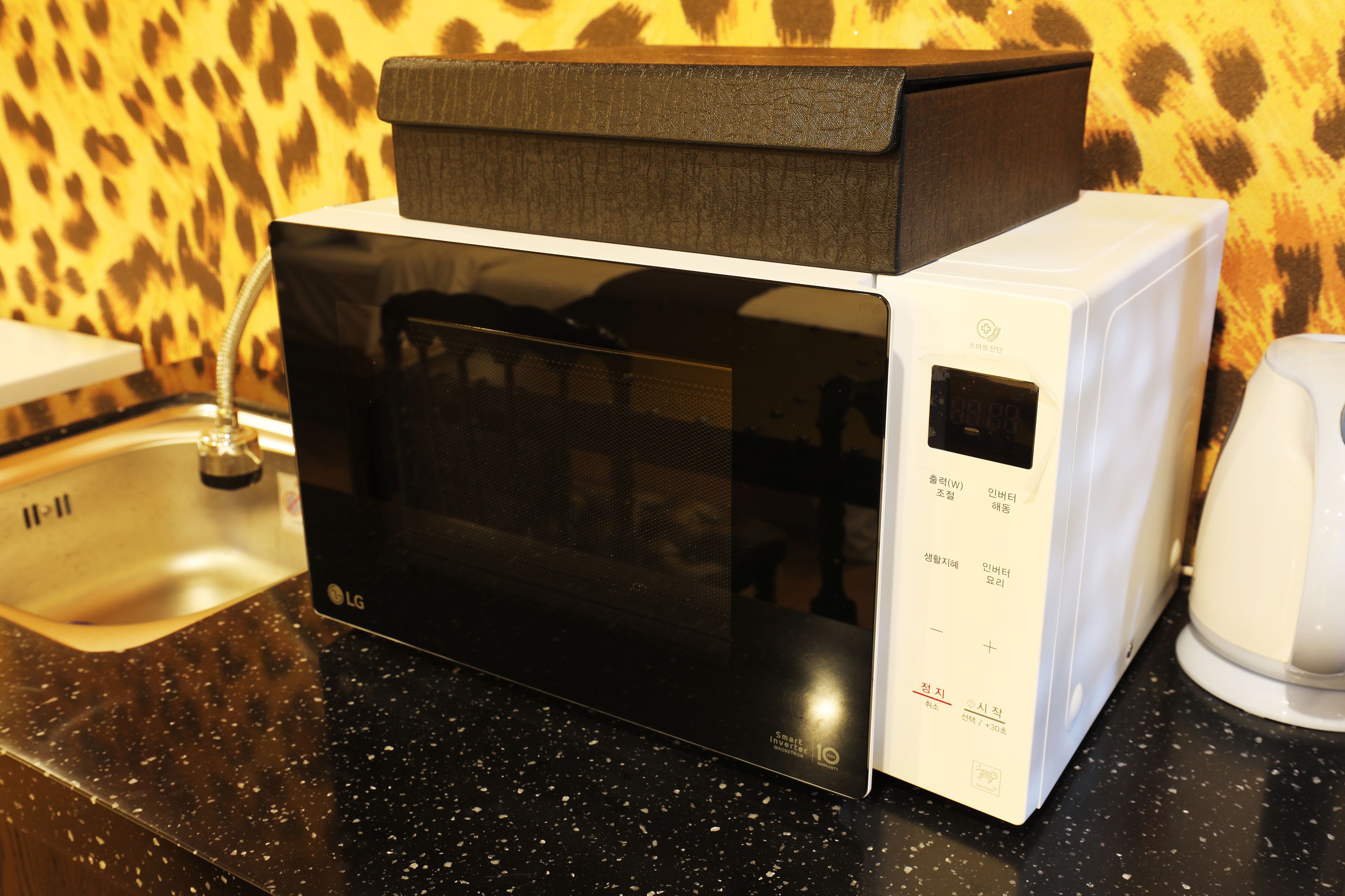 Um forno de micro-ondas com visor digital, painel de controle e cabo de alimentação.