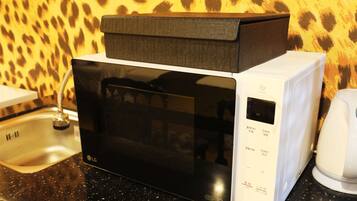Um forno de micro-ondas com visor digital, painel de controle e cabo de alimentação.