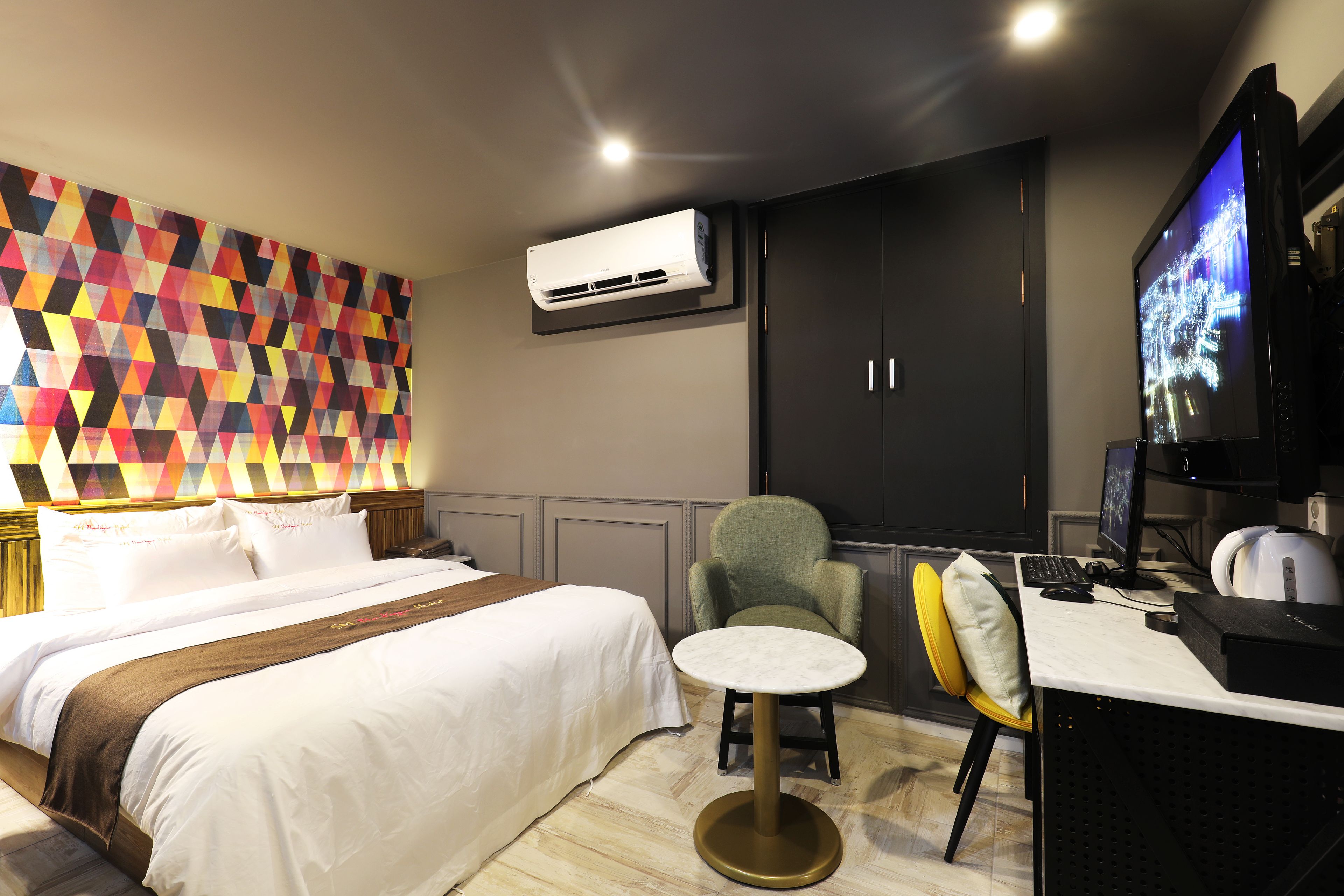 Une chambre d’hôtel équipée d’un lit, d’un bureau avec un ordinateur, d’une chaise, d’un climatiseur et d’un téléviseur.