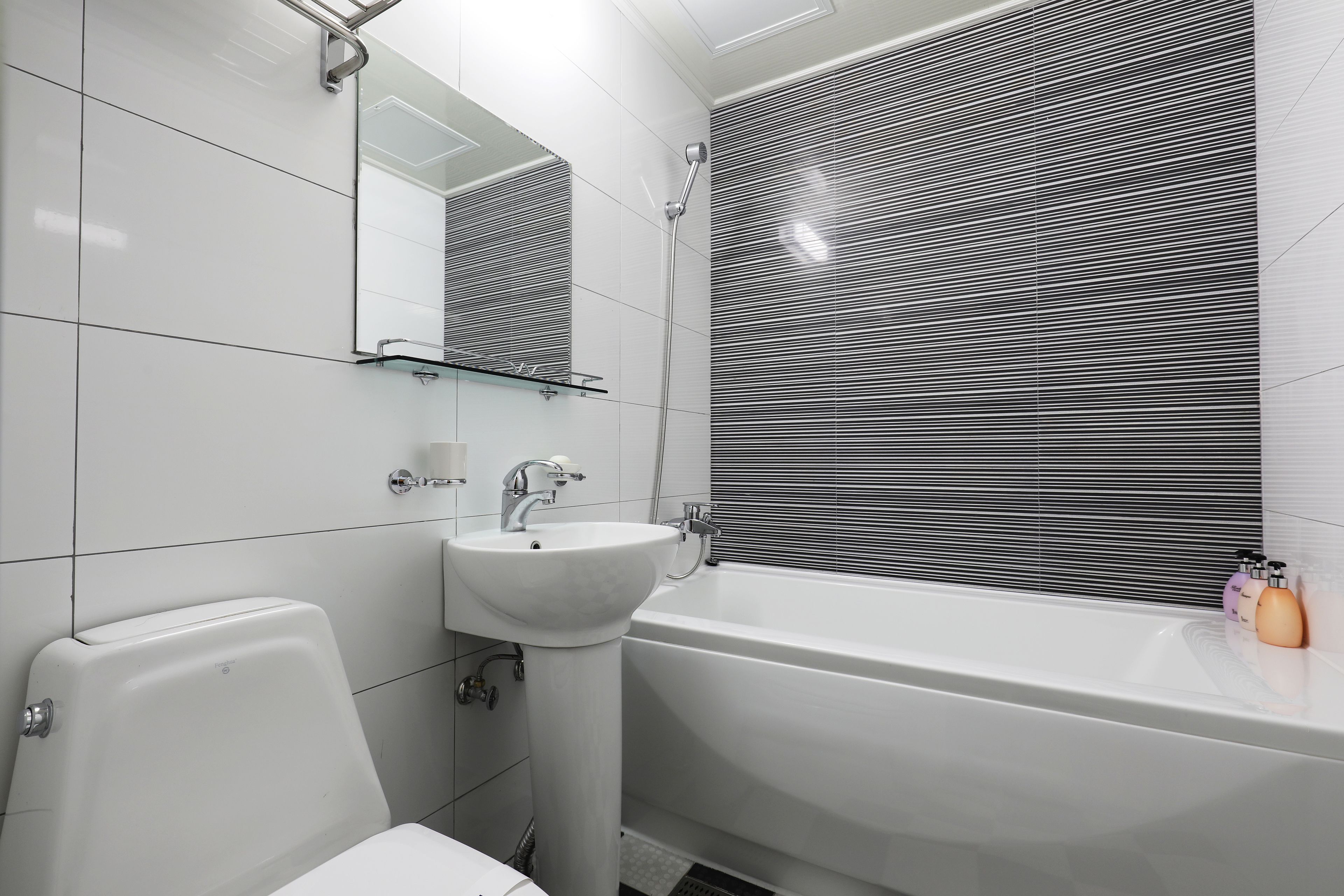 Une salle de bain moderne avec un lavabo, des toilettes et une baignoire, le tout de couleur blanche.