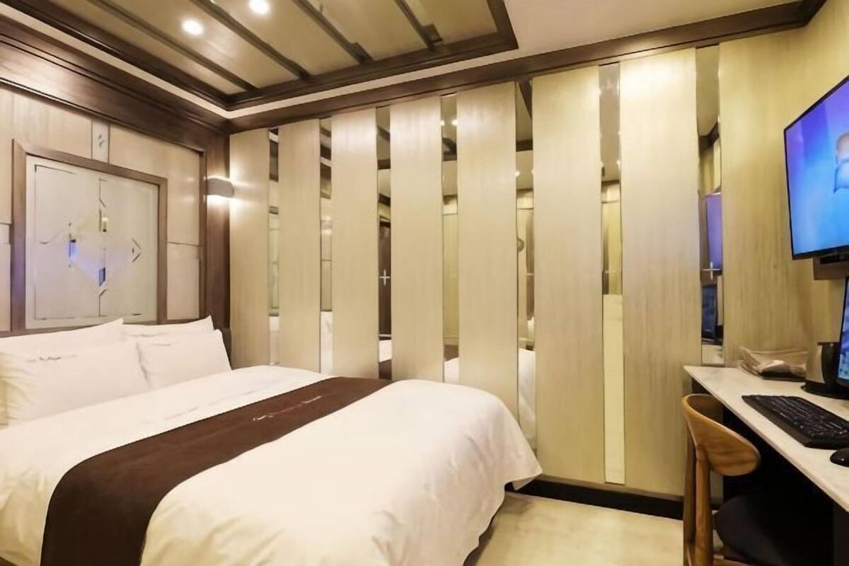 Una habitación de hotel con una cama, un escritorio con una computadora y una silla.