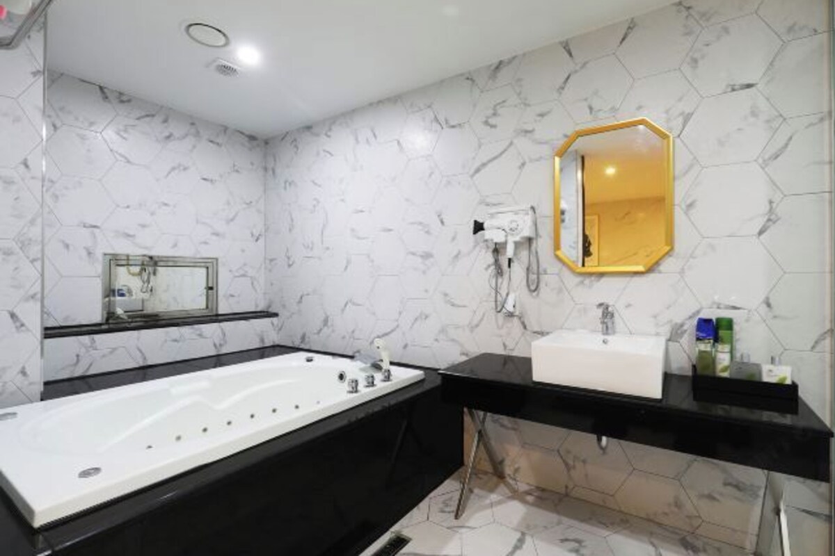 A modern bathroom with a black vanity, white sink, and a large bathtub.