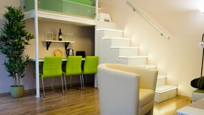 Un espacio de estar moderno con comedor, una escalera y una planta.
