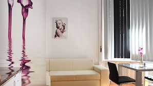 Una sala moderna con un sofá, una mesa de comedor con un jarrón de flores y obras de arte en la pared.