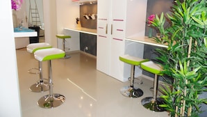 Una cocina moderna con armarios blancos, encimera de acero inoxidable y taburetes de bar verdes.
