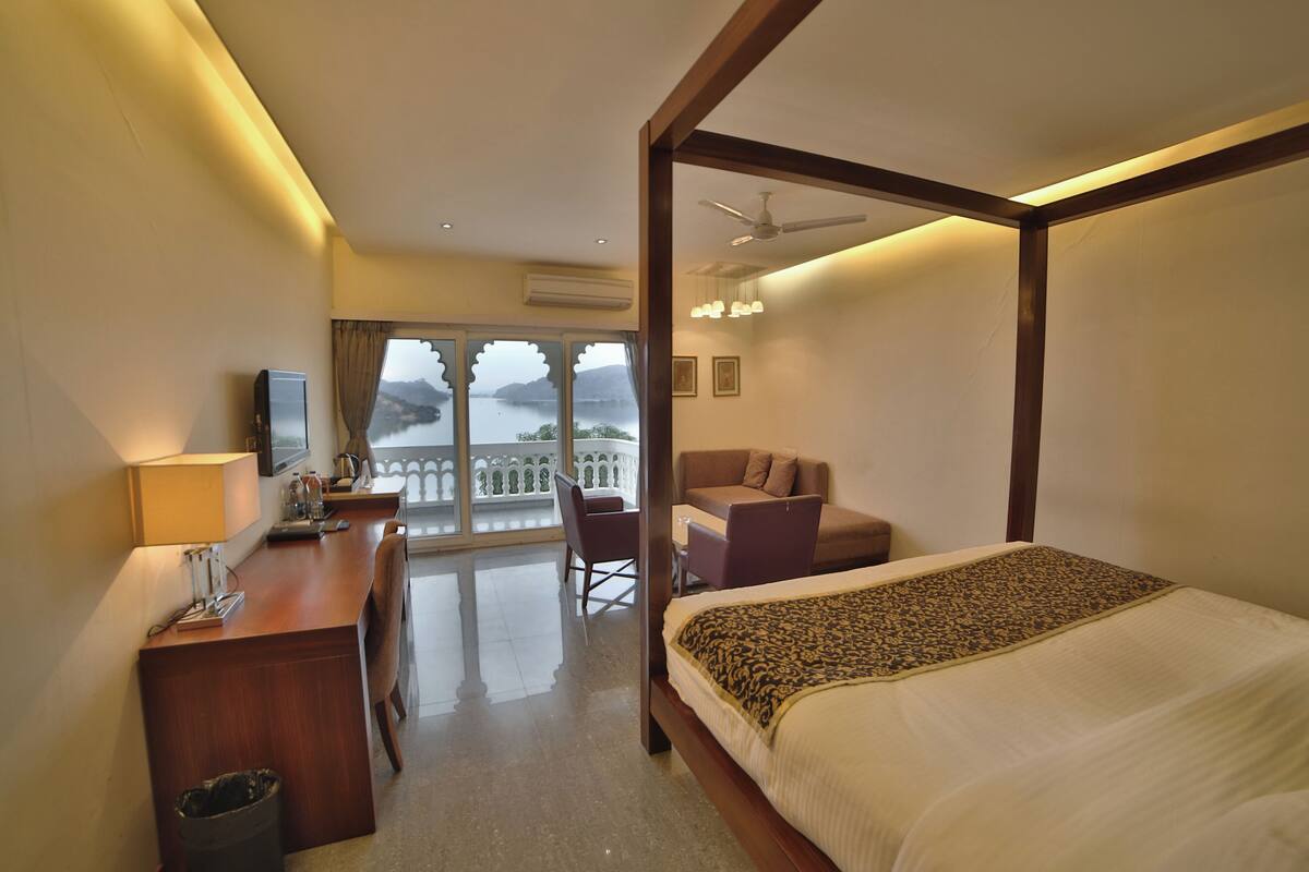 Ein Hotelzimmer mit Bett, Schreibtisch, Stuhl und einem Balkon mit Blick.