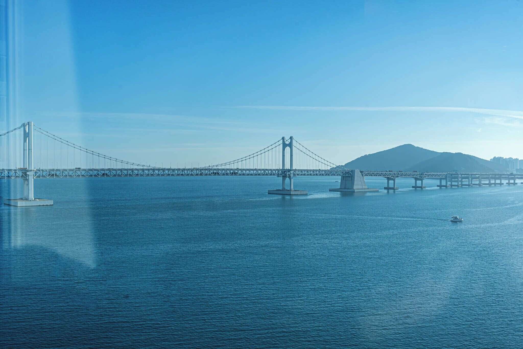 A large suspension bridge over a body of water with a mountain in the background.