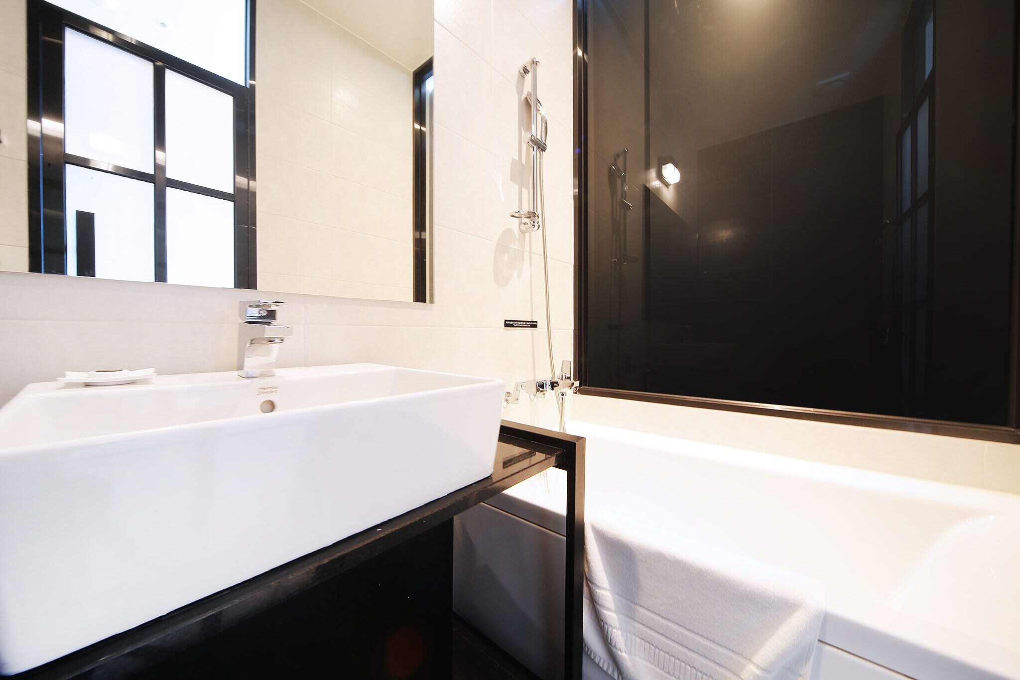 Een moderne badkamer met een grote witte wastafel, een vrijstaand bad en een douchecabine met glazen wanden.