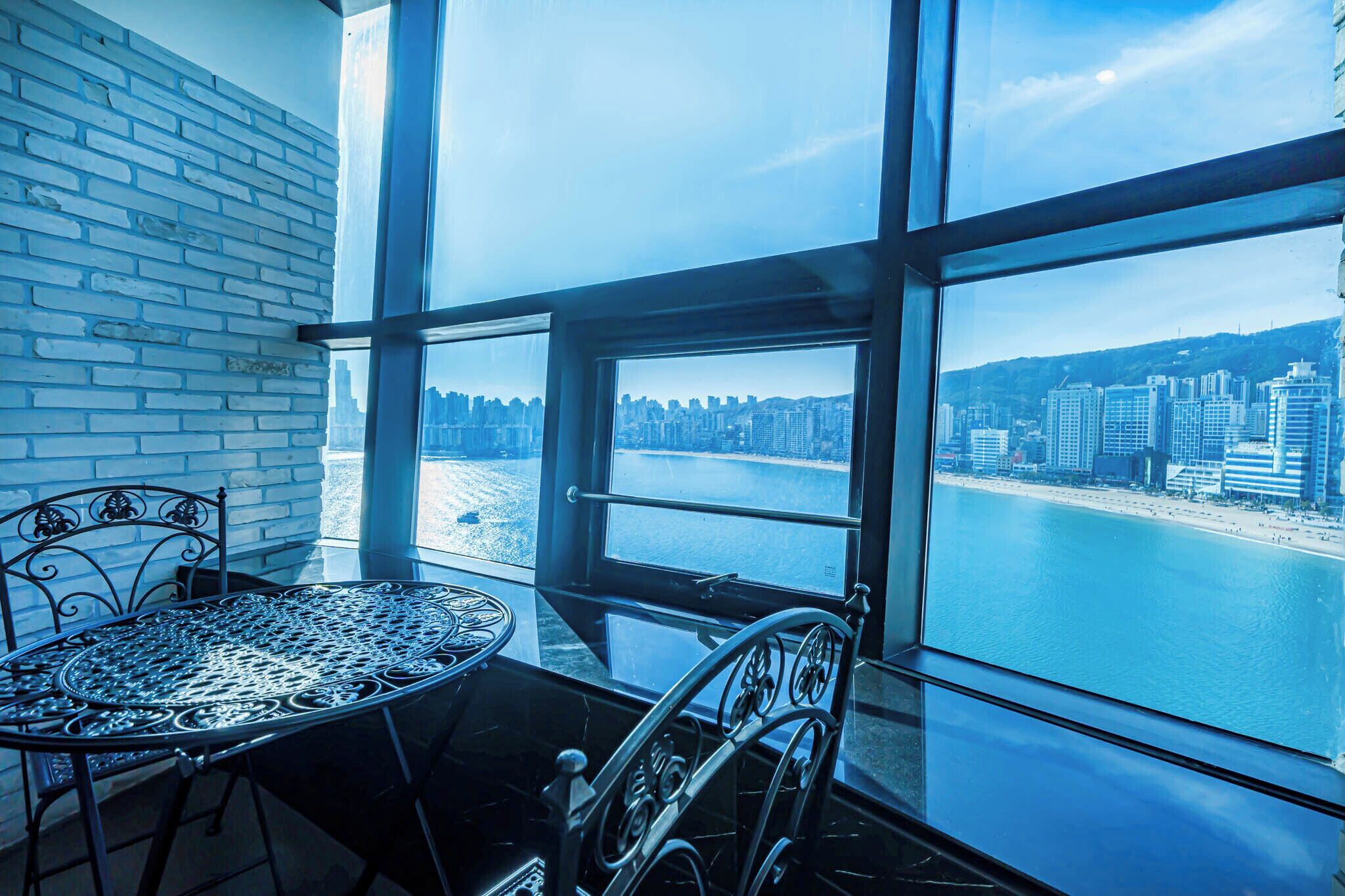 A room with a large window overlooking a waterfront cityscape.