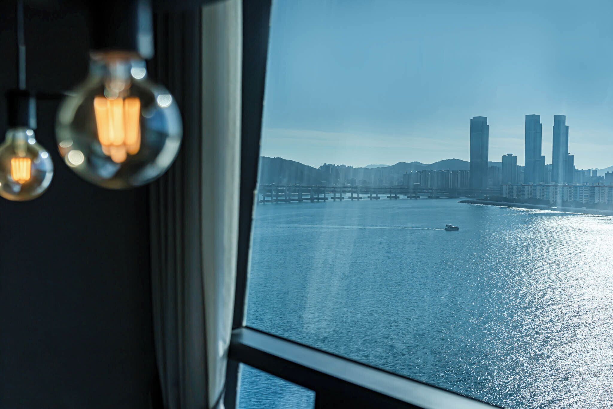 A view of a city skyline with tall buildings and a bridge over a body of water.