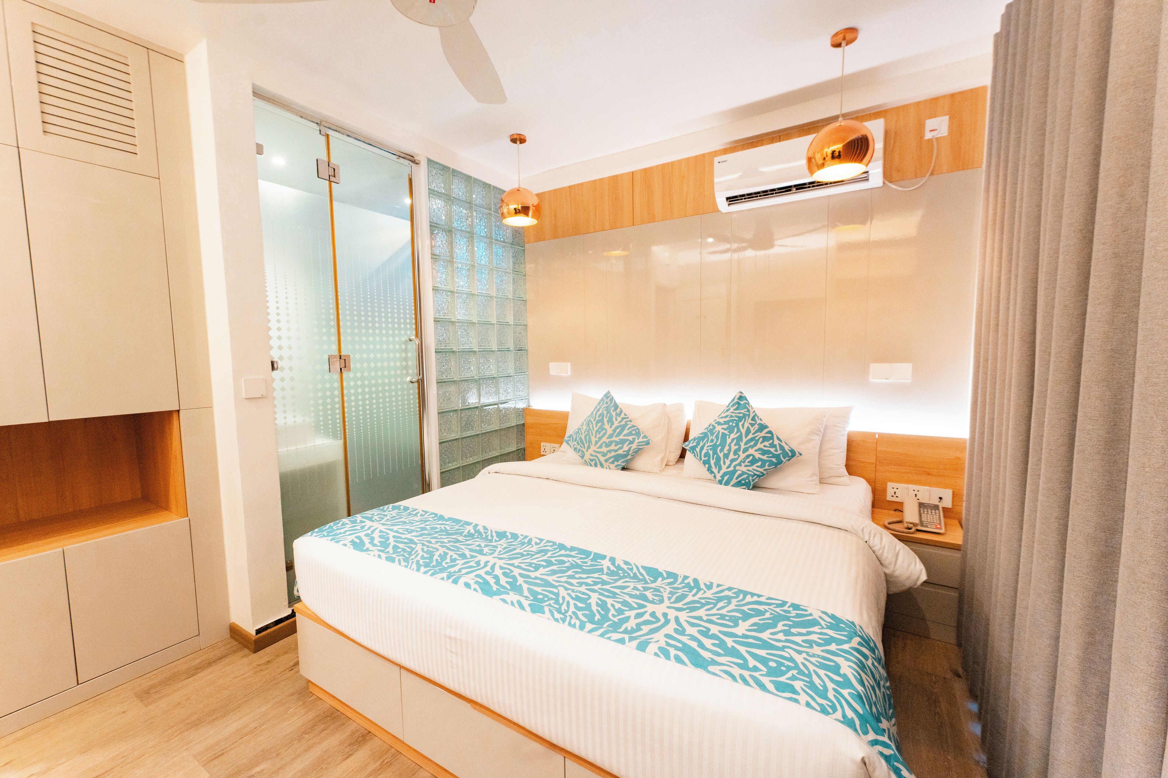 Habitación de hotel moderna con una cama grande, un armario, una puerta corredera de cristal y un equipo de aire acondicionado integrado.