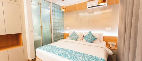 Habitación de hotel moderna con una cama grande, un armario, una puerta corredera de cristal y un equipo de aire acondicionado integrado.