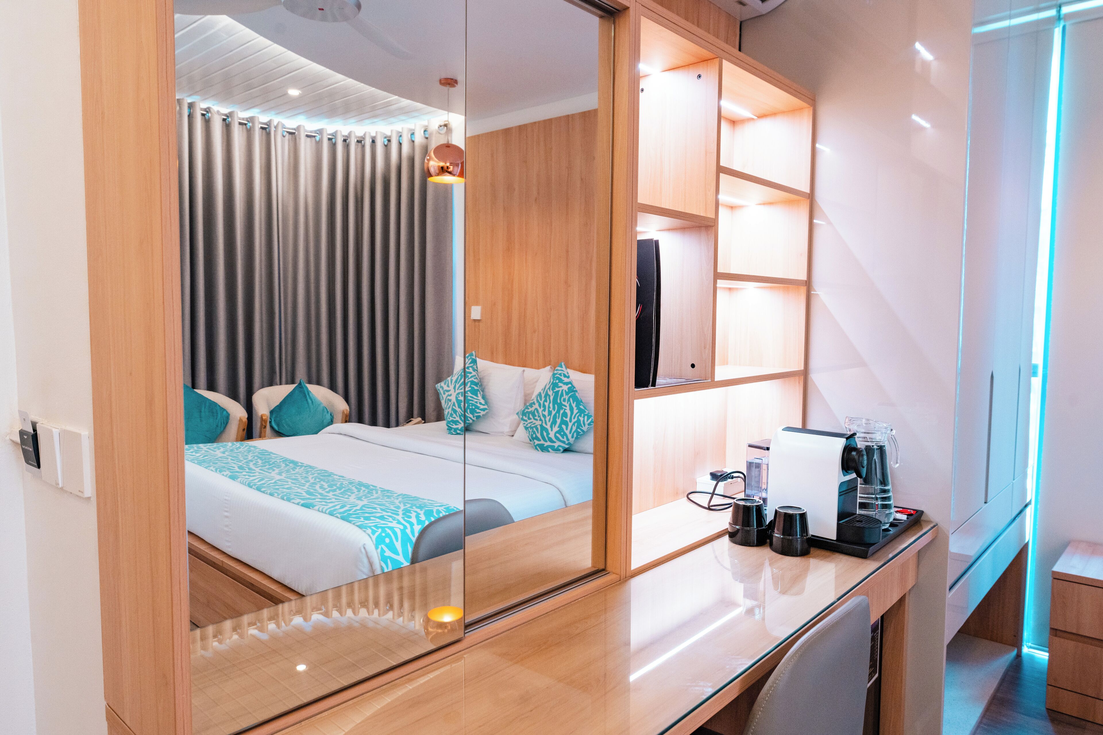 Habitación de hotel moderna con una cama grande, un escritorio con cafetera y un espejo que refleja la habitación.