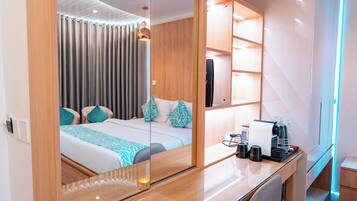 Habitación de hotel moderna con una cama grande, un escritorio con cafetera y un espejo que refleja la habitación.