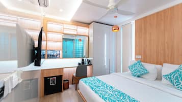 Una habitación de hotel con cama, escritorio con silla, armario y ventilador de techo.