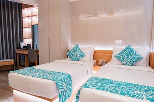A hotel room with two beds, a desk, and a minibar.