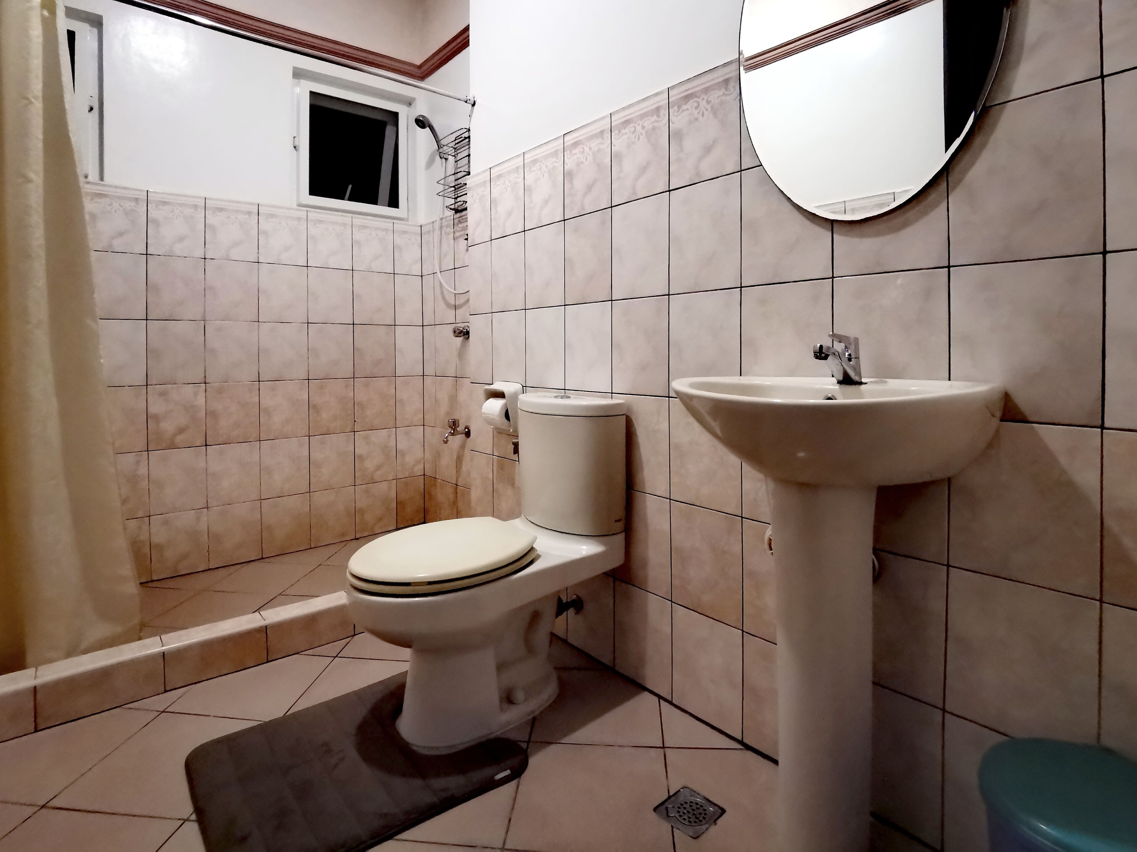 A bathroom with a toilet, sink, and shower.