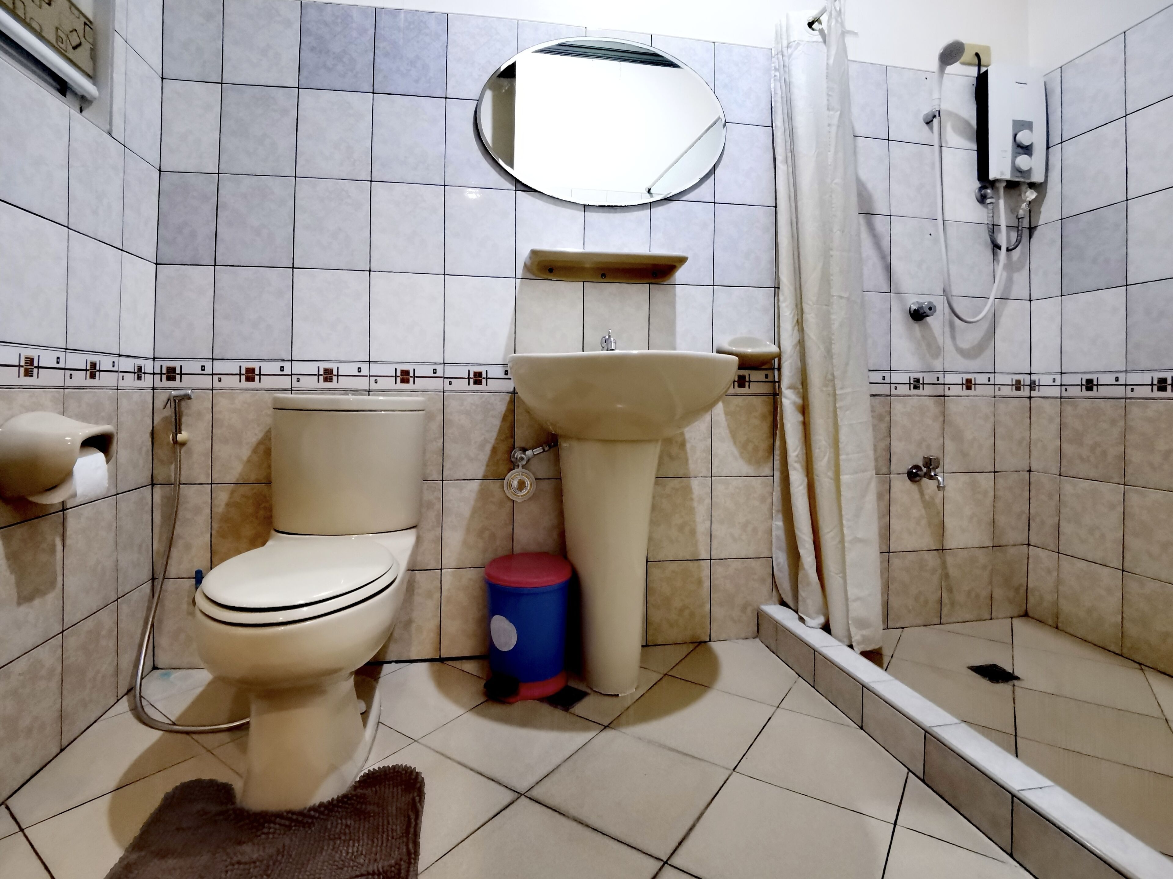 Un baño con inodoro, lavamanos, ducha y espejo.