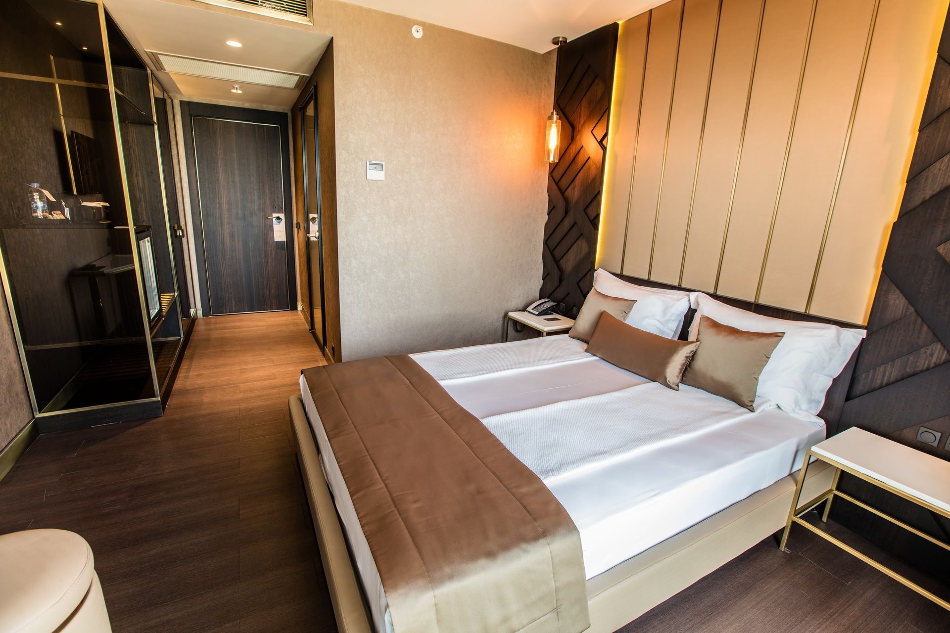 A hotel room with a large bed, bedside tables, a desk, and a mirror.
