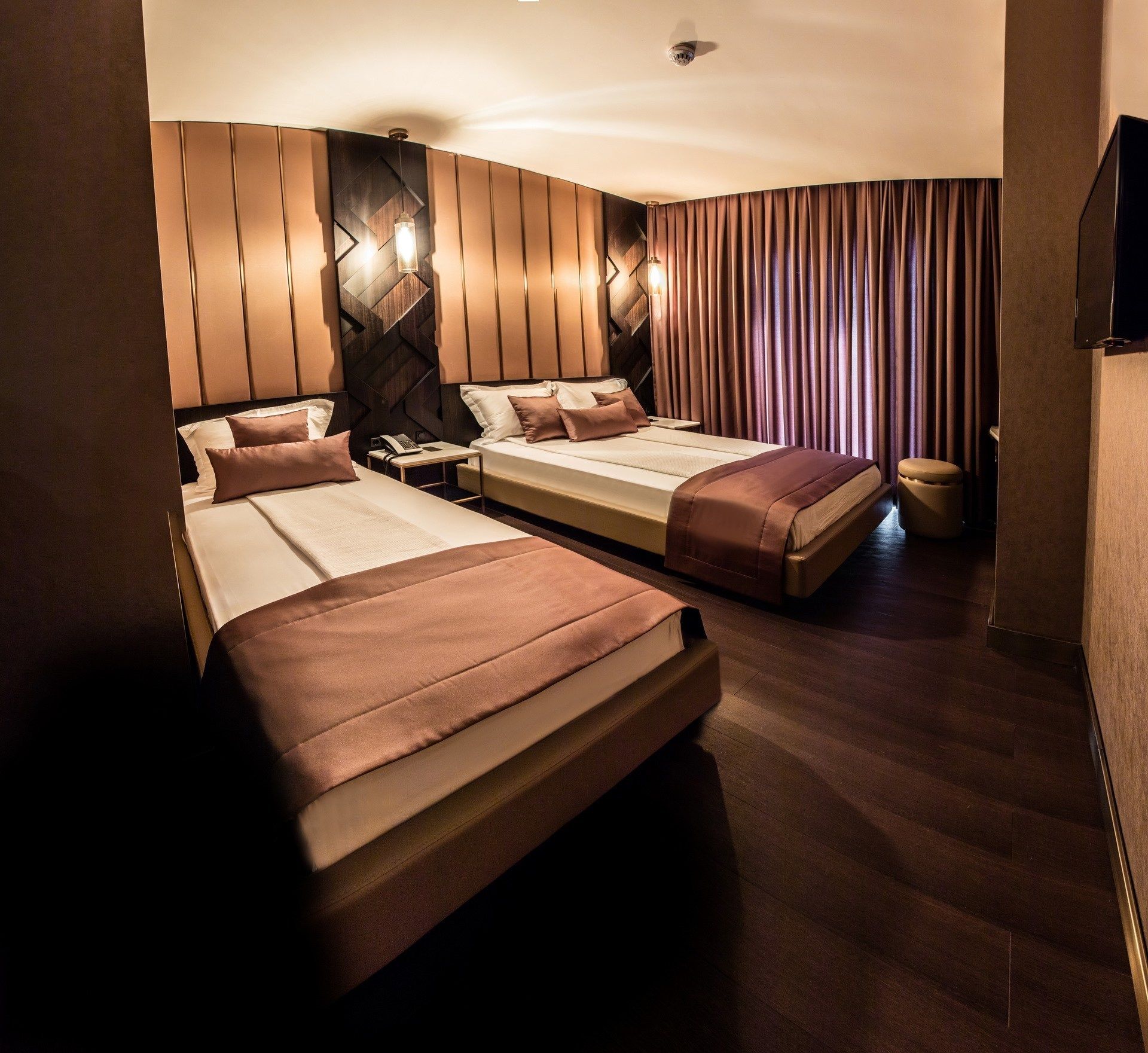 A hotel room with two beds, a desk, a telephone, and a television.