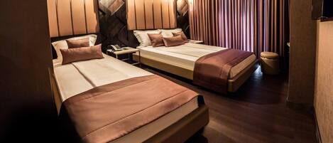 A hotel room with two beds, a desk, a telephone, and a television.