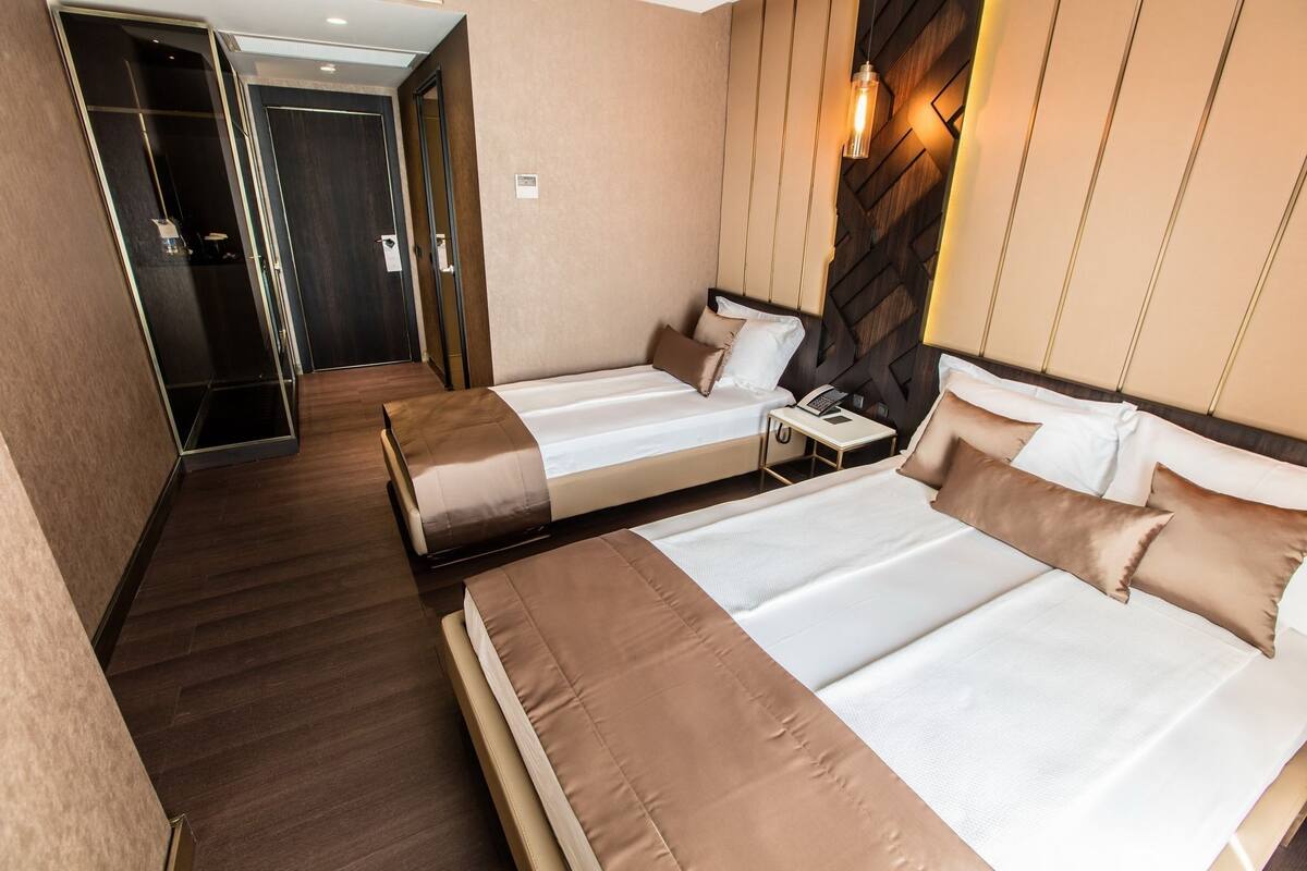 Ein Hotelzimmer mit zwei Betten, einem Schrank und einem Spiegel.