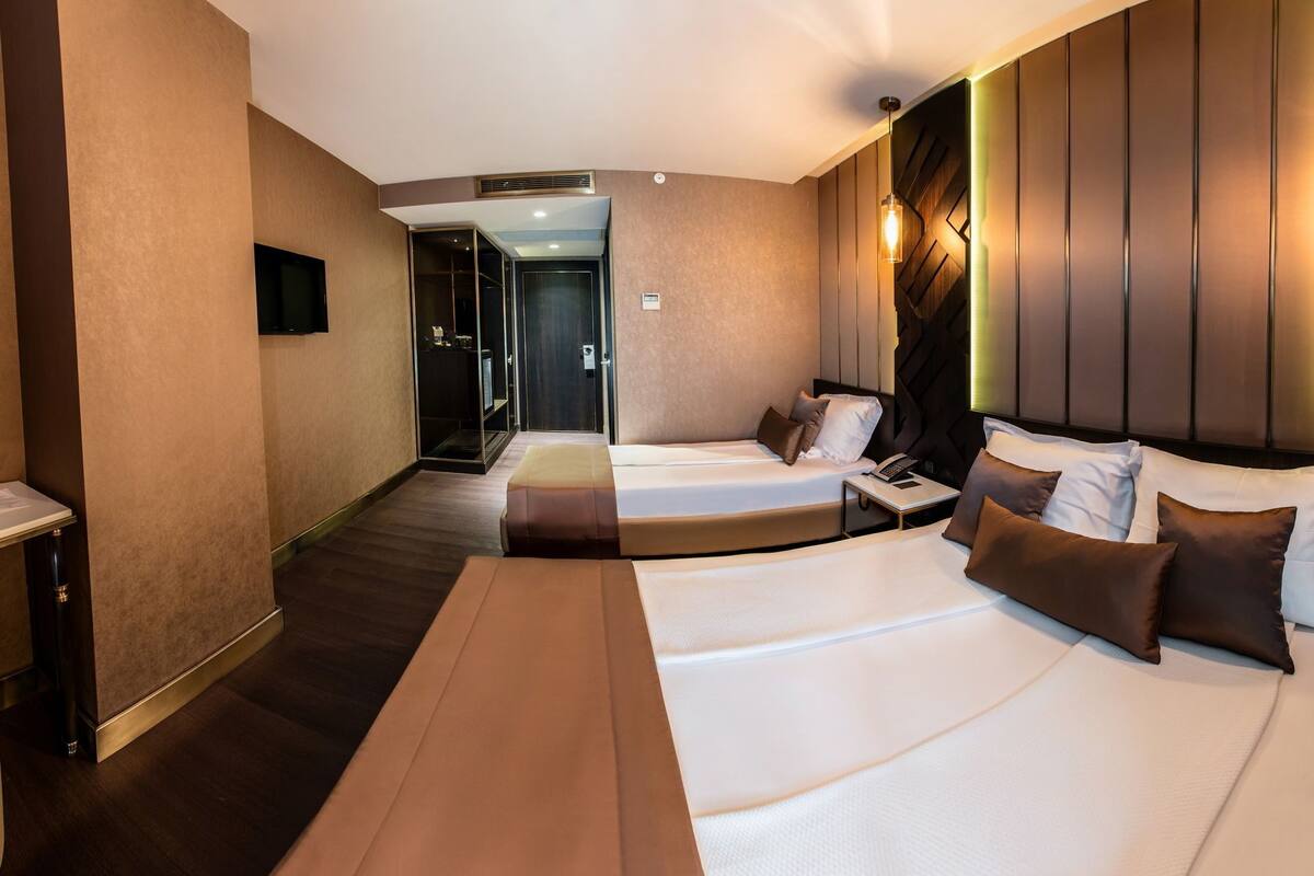 Ein Hotelzimmer mit zwei Betten, einem Schreibtisch und einem Kleiderschrank.