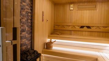 Un sauna avec des bancs en bois, un mur en pierre et un plafond en bois doté d’une lucarne.