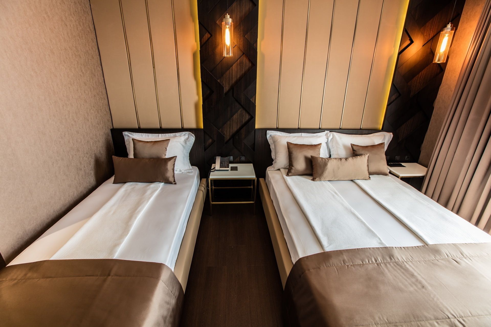Een hotelkamer met twee bedden, elk voorzien van een kussen en nachtkastje.