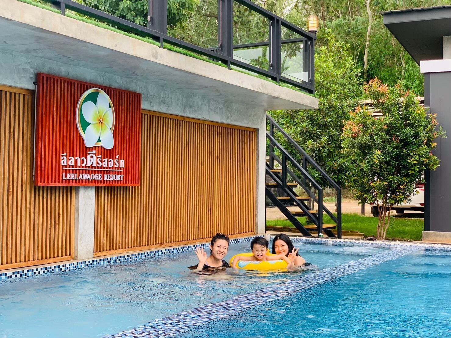 Una piscina con cubierta de madera y un letrero que indica Leelawadee Resort.