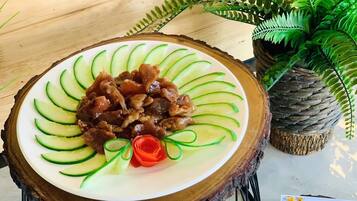 Un plato de chicharrón frito especial de Leclawadee sobre una mesa de madera con una planta de helecho al fondo.